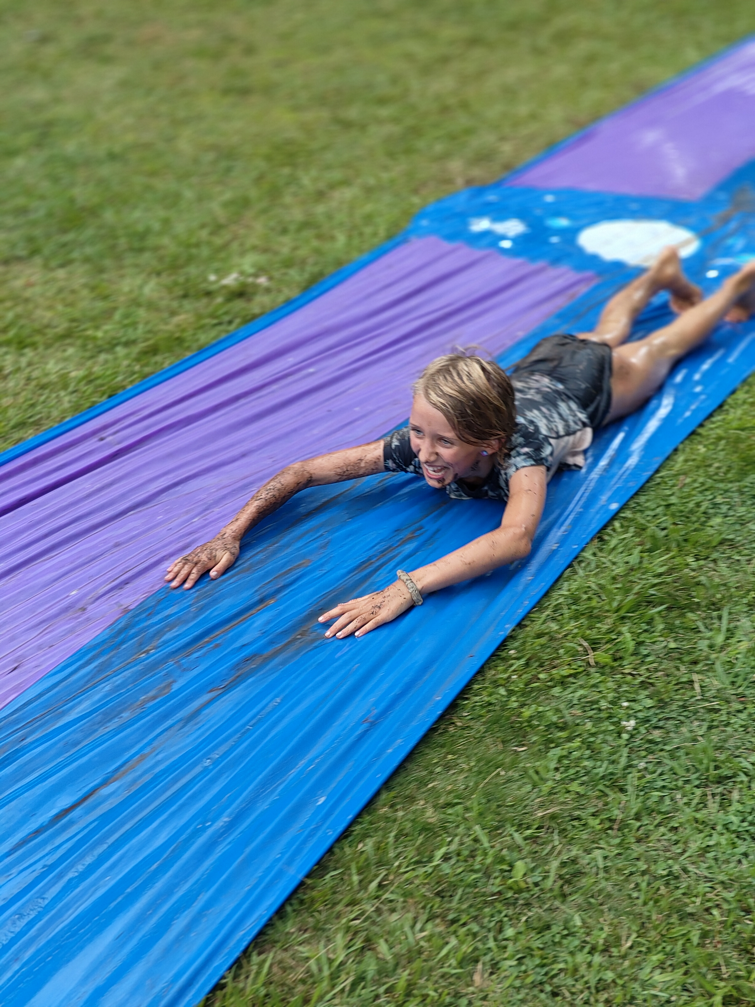 Child laughing on a slip-and-slide in summer