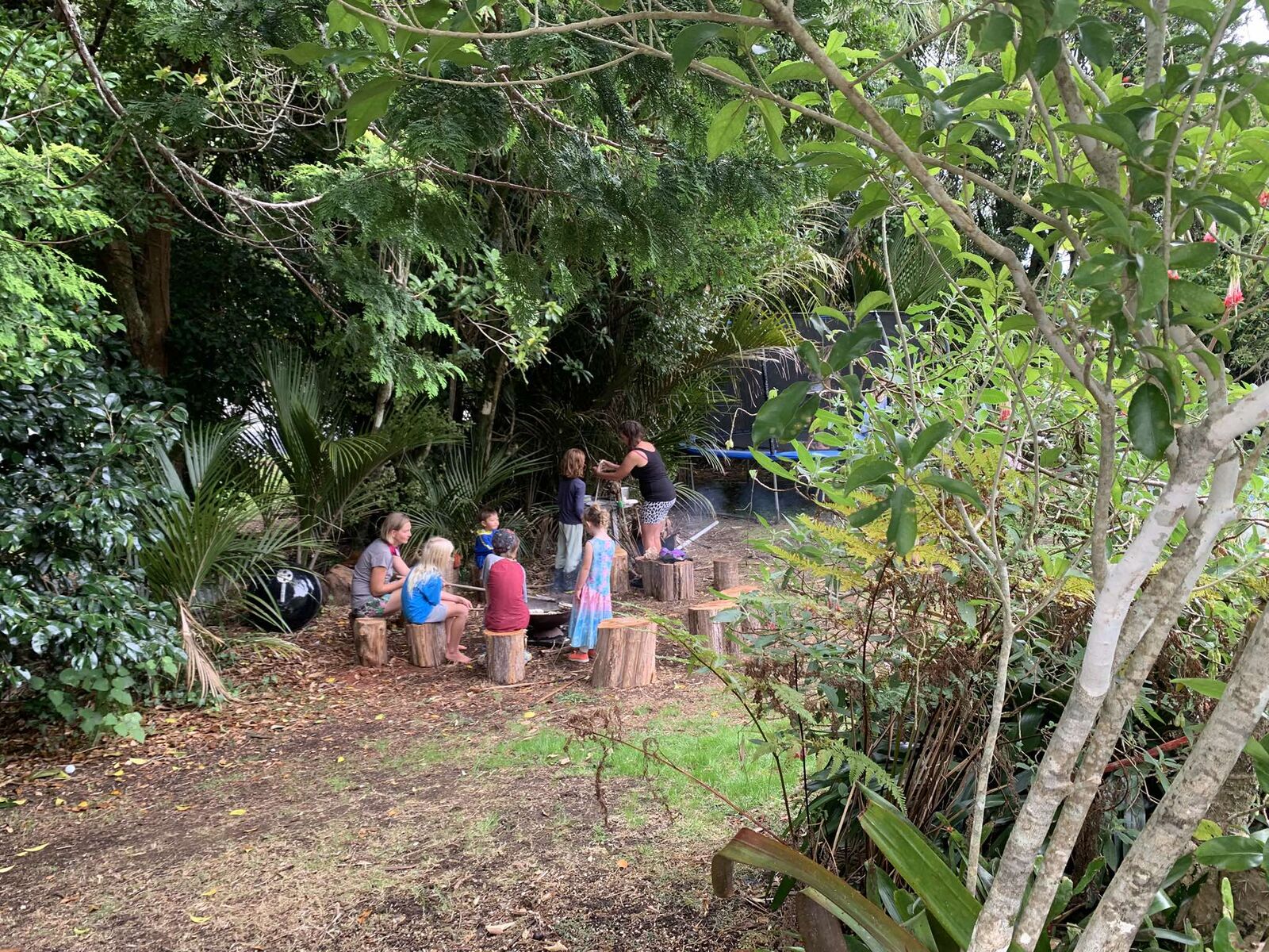 Children gathered around the fire at The Bush Base, Waiatarua